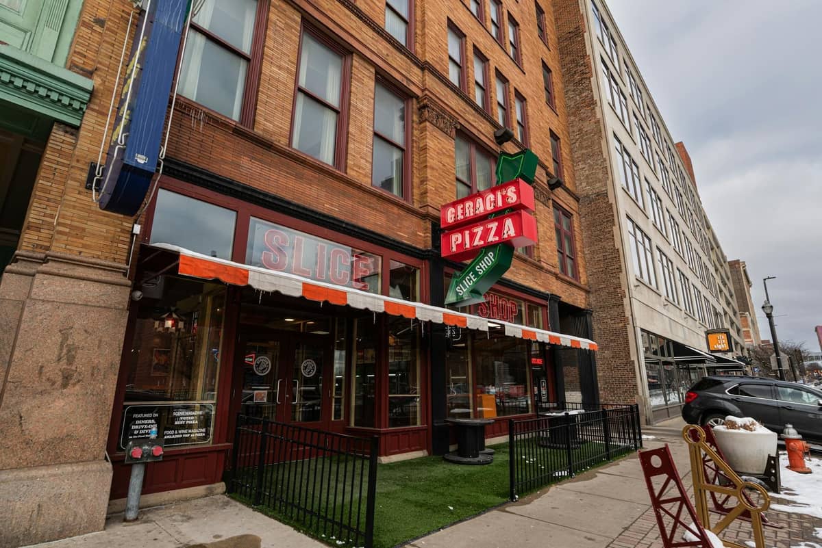 Straßenansicht eines Pizzarestaurants mit rotem Neonschild, großen Fenstern und einem historischen Backsteingebäude in Chicago