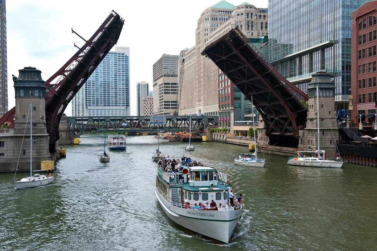Eine Bootsfahrt auf dem Chicago River mit hochgezogenen Klappbrücken und historischen Gebäuden der Innenstadt im Hintergrund.