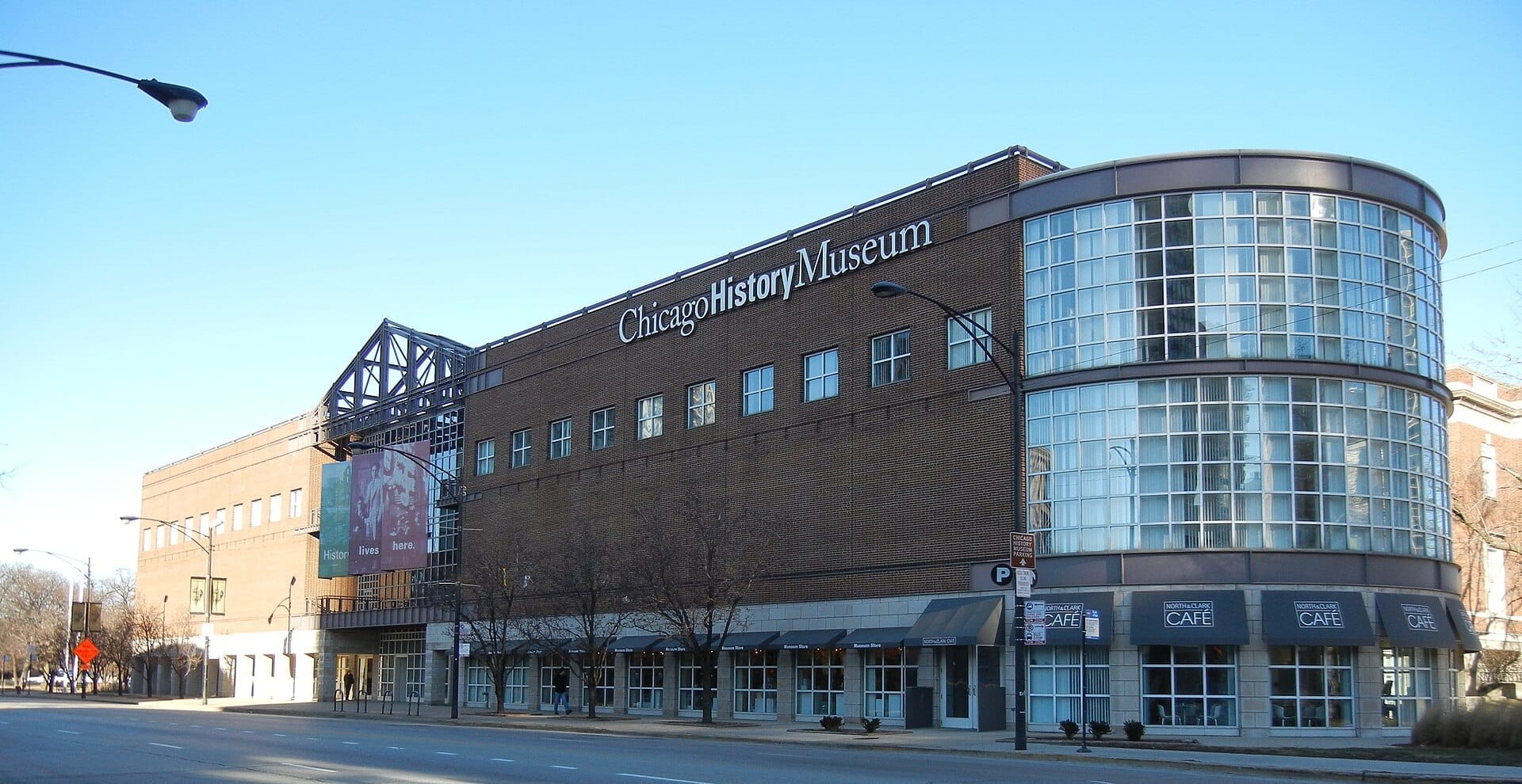 Vista dalla strada dell'edificio del Chicago History Museum con la sua moderna facciata in vetro, l'esterno in mattoni e una chiara segnaletica in una giornata di sole.