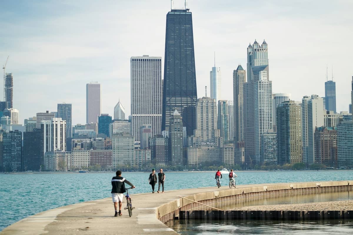 Des personnes à vélo et à pied le long du Lakefront Trail de Chicago avec une vue dégagée sur la skyline et le lac par une ensoleillée journée d'été.