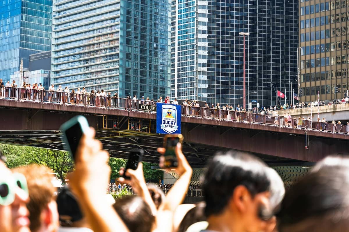 Foule estivale rassemblée sur un pont au-dessus de la Chicago River avec les gratte-ciel du centre-ville en arrière-plan par une journée ensoleillée.