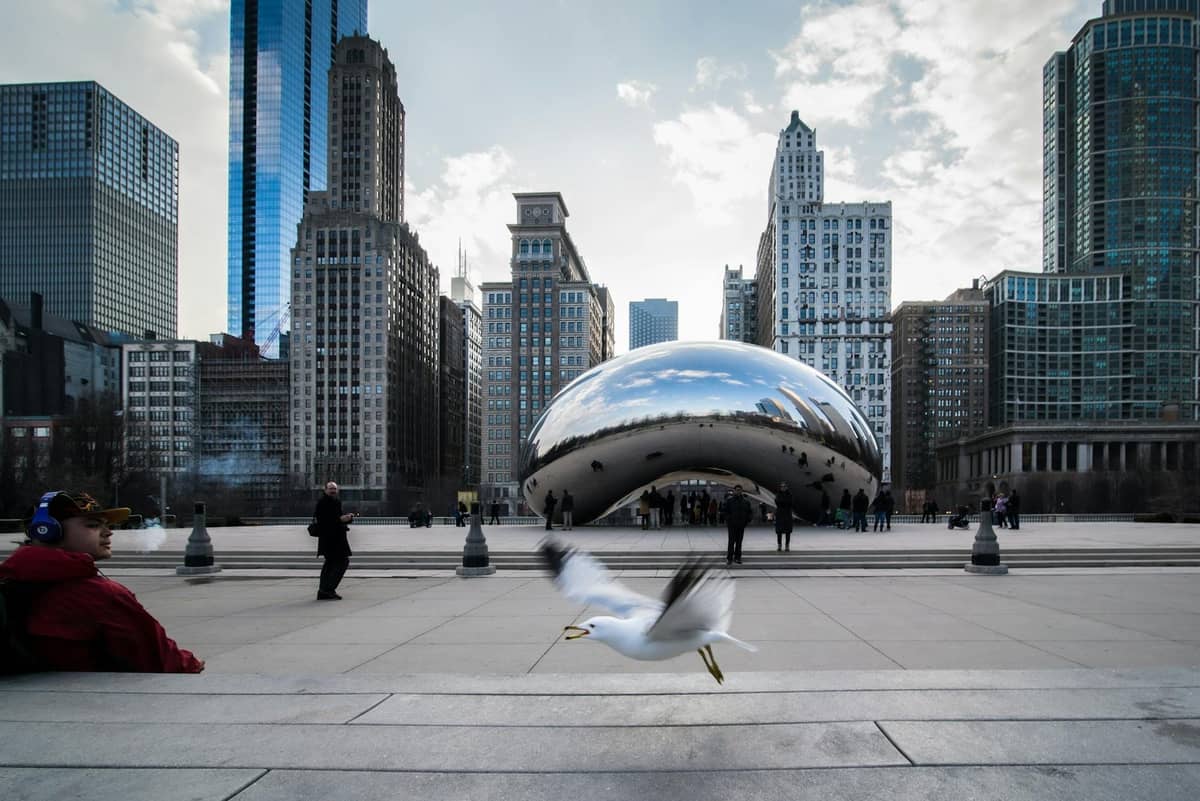 Cloud Gate Skulptur mit Menschen und Chicagoer Wolkenkratzern im Hintergrund an einem Wintertag.