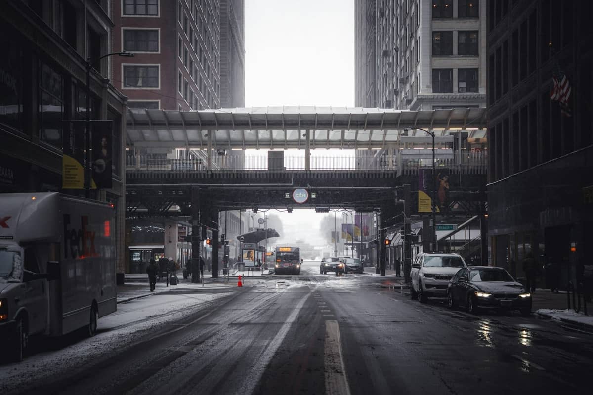Verschneite Innenstadt von Chicago mit Autos, Bussen und den erhöhten Gleisen der CTA 'L'-Bahn im Winter.
