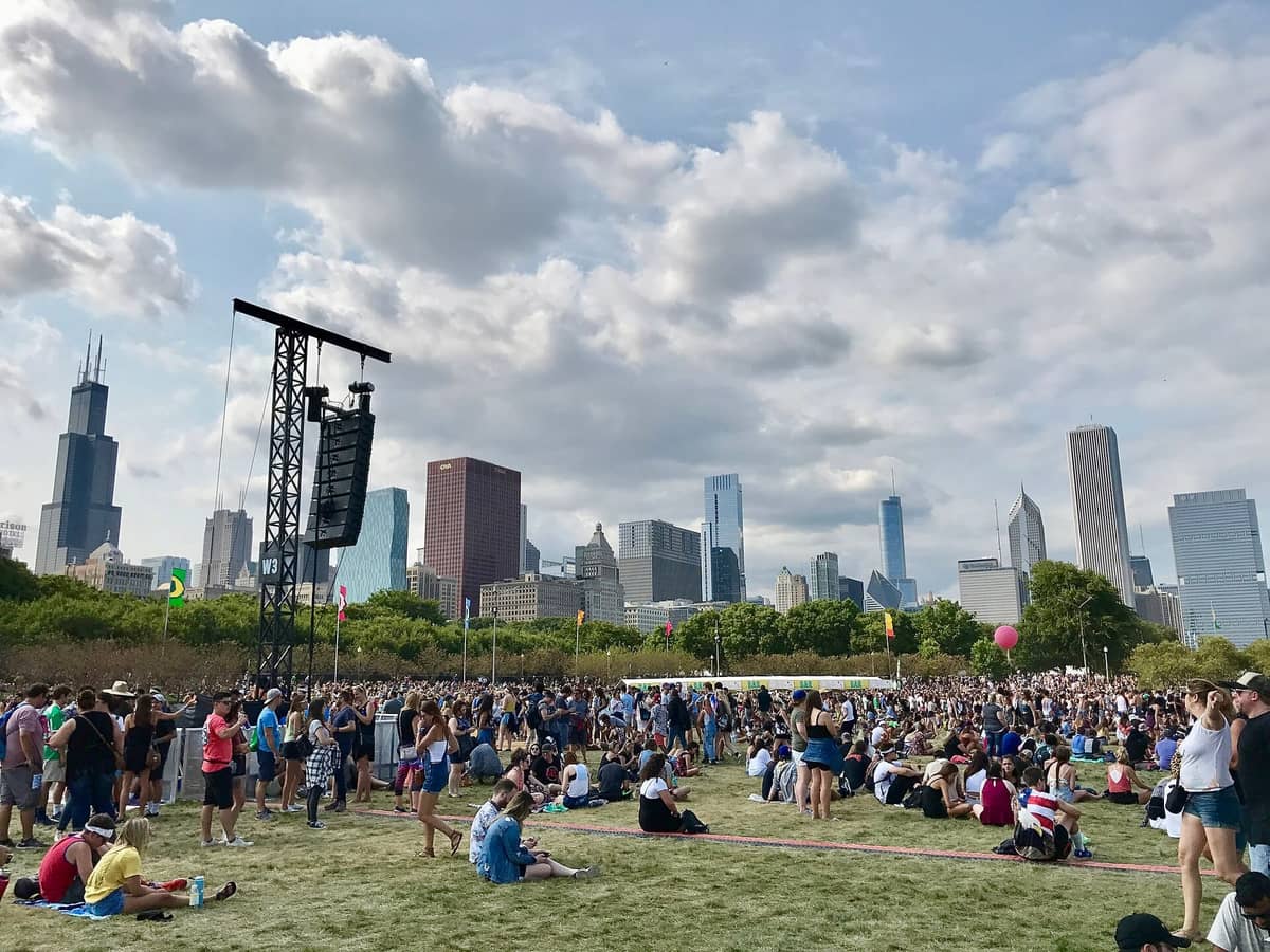 Grande folla riunita al Grant Park per Lollapalooza, con lo skyline di Chicago e la Willis Tower visibili sotto un cielo parzialmente nuvoloso.
