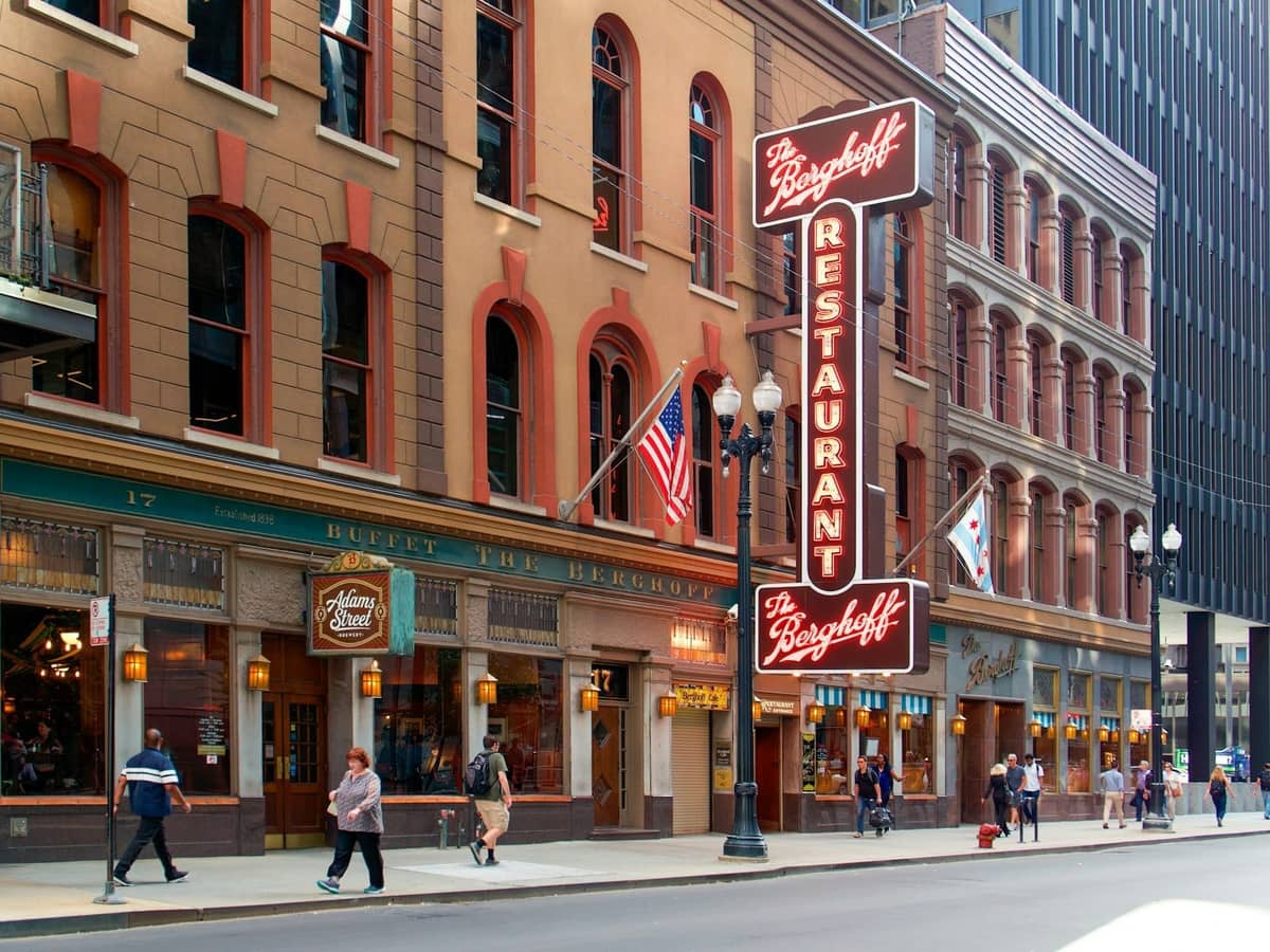 Vista stradale del Berghoff Restaurant nel centro di Chicago, con persone che camminano e bandiere di Chicago esposte.