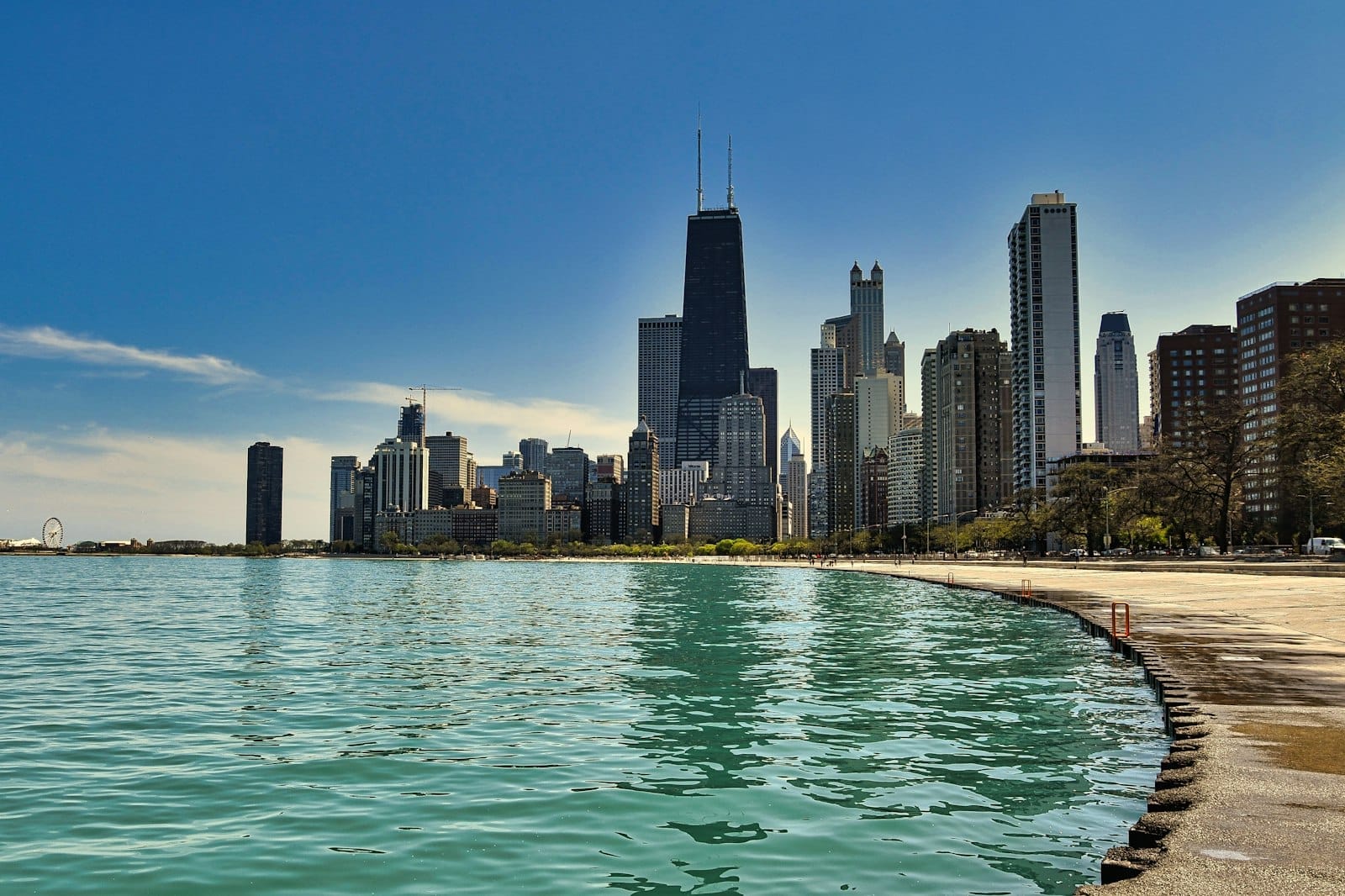 Skyline de Chicago vista da orla do lago, dia ensolarado com água calma e arranha-céus icônicos sob um céu azul limpo.