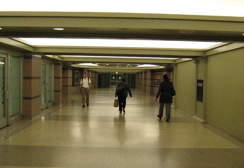 Ampio corridoio ben illuminato all'interno del Chicago Pedway, con tre persone che camminano su pavimenti lucidati e porte in vetro lungo le pareti.