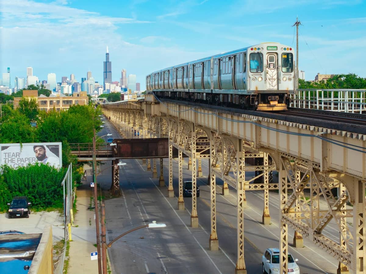 Tren elevado Chicago L circulando por una vía elevada con el horizonte de la ciudad y la Willis Tower visibles al fondo.