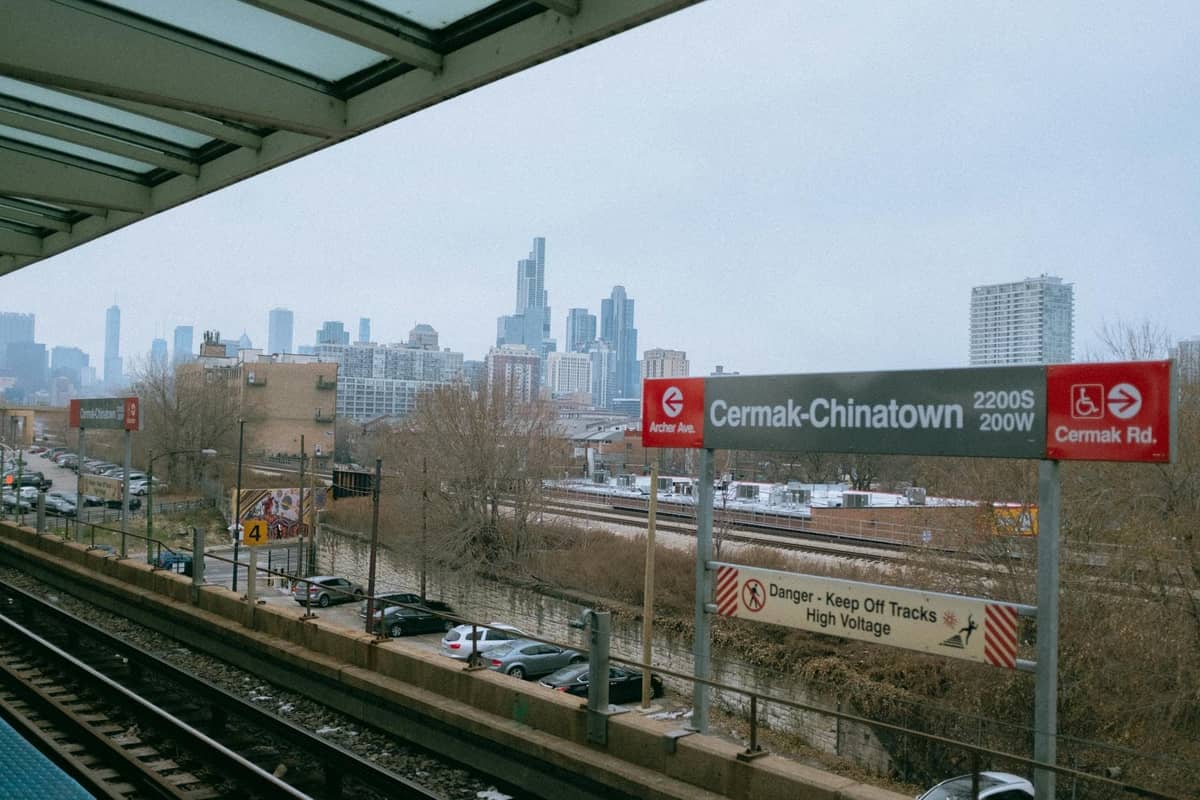 Bahnsteig der Chicago CTA L-Bahn an der Station Cermak-Chinatown mit der Stadtsilhouette im Hintergrund und sichtbaren Transitschildern.