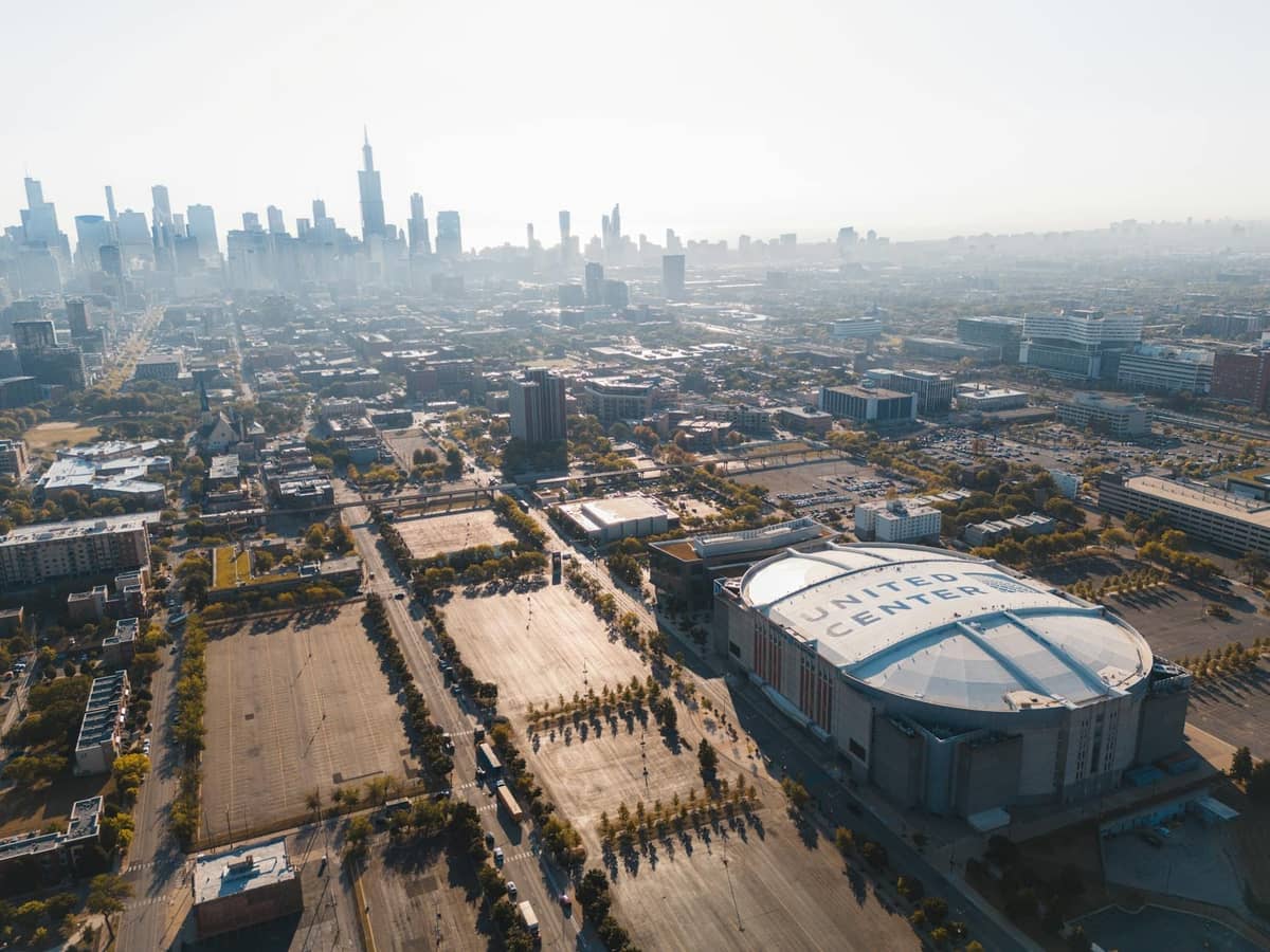 Vista aerea dello skyline di Chicago con l'United Center prominente in primo piano, circondato da edifici cittadini e parcheggi.