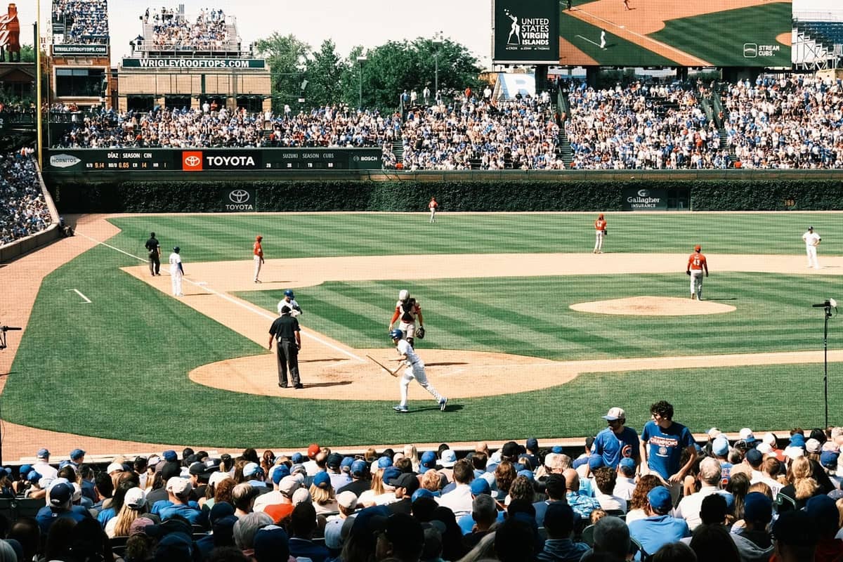 Folla stipata al Wrigley Field che guarda una partita di baseball, con il battitore all'home plate e l'iconico edera del campo esterno visibile.