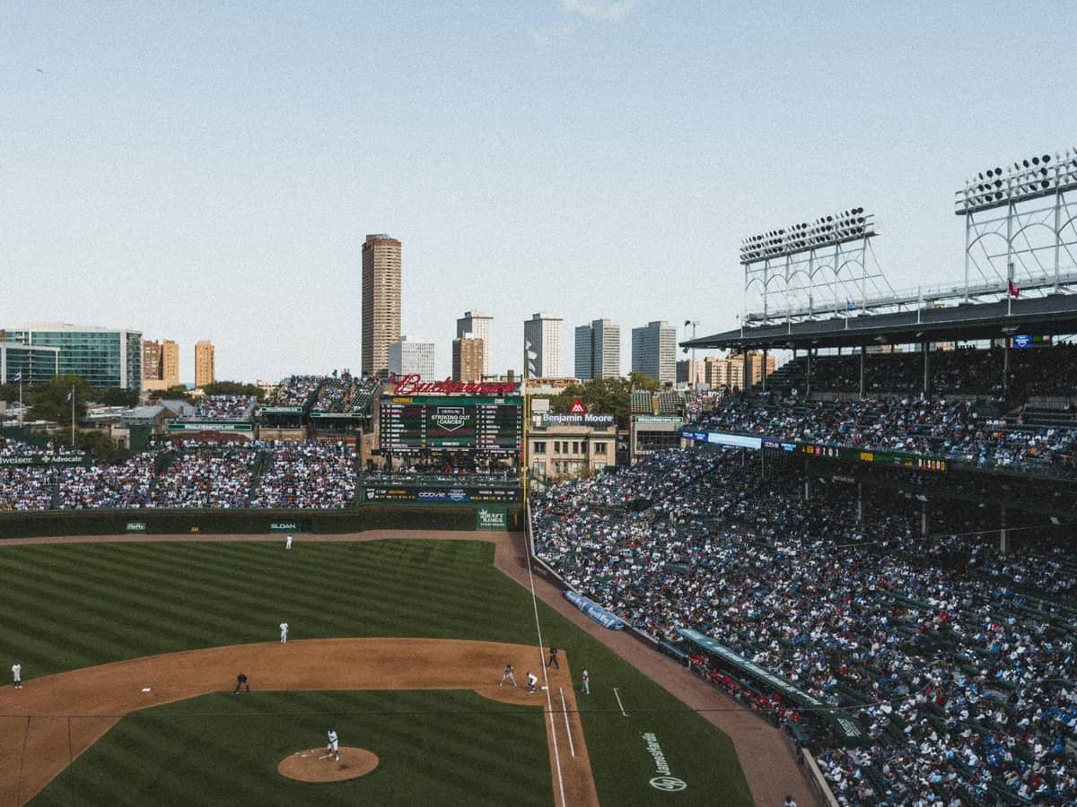 Vista ampia di uno stadio di baseball affollato a Chicago con lo skyline della città sullo sfondo in una giornata serena.