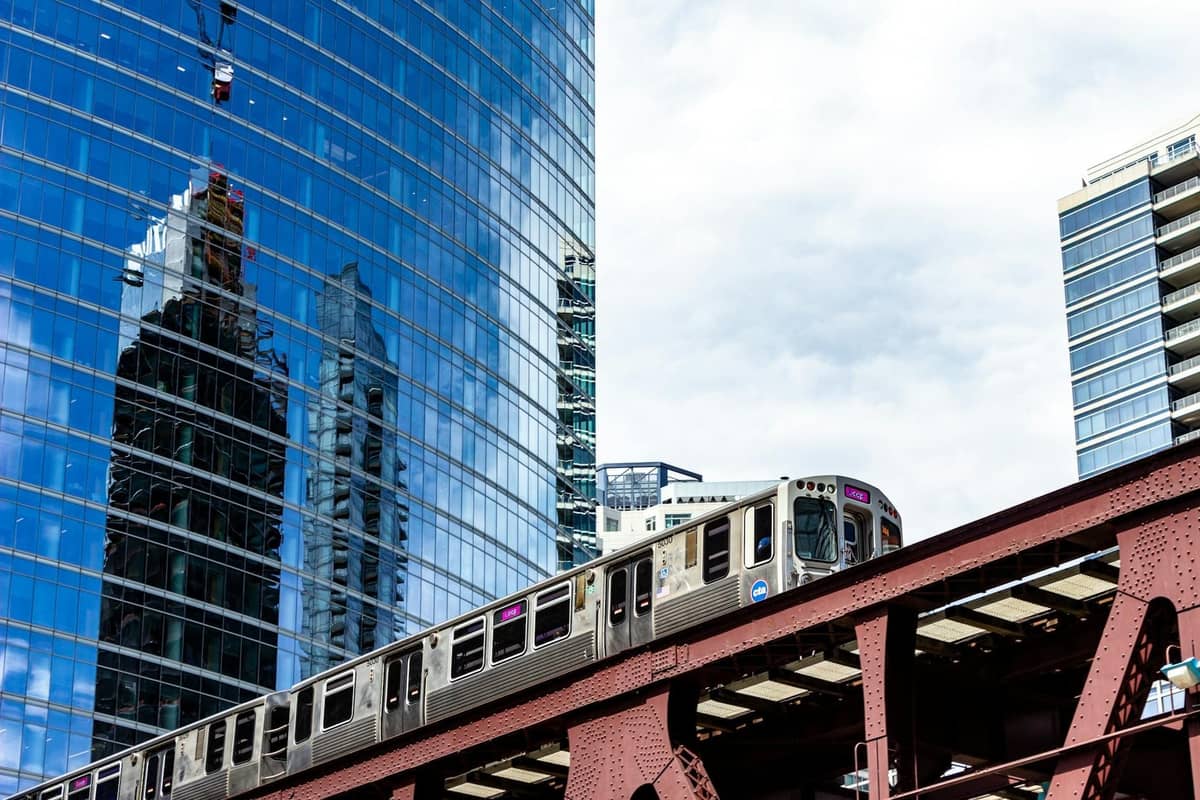 Chicago 'L' train traveling through downtown with glass skyscrapers in the background on a clear day