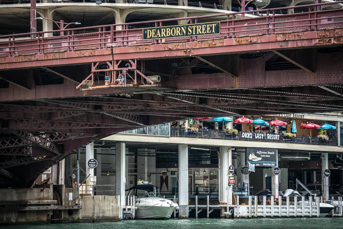 Blick auf die Dearborn Street Bridge in Chicago mit sichtbaren Außensitzplätzen von Restaurants am Flussufer.