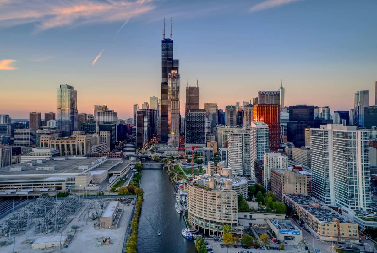 Luftaufnahme der Innenstadt von Chicago mit dem Fluss, der durch die Wolkenkratzer fließt, mit markanten Stadtvierteln und Stadtbild bei Sonnenuntergang.