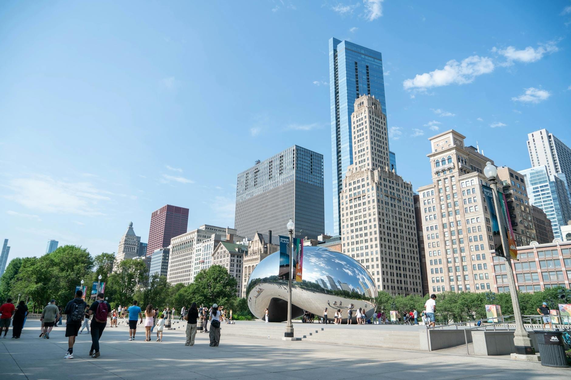 Pessoas passeando pelo Millennium Park com a escultura The Bean e o skyline de Chicago ao fundo em um dia ensolarado.