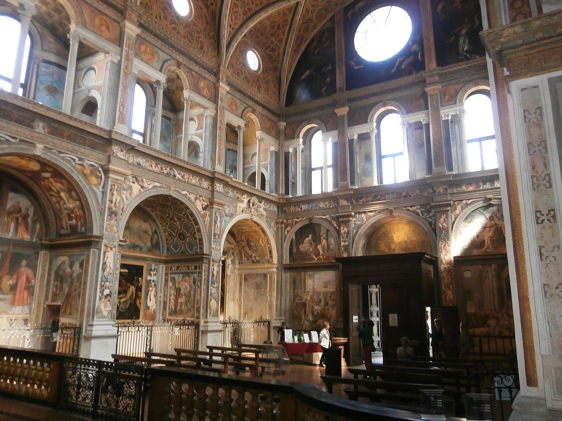 Vista interna della Chiesa di San Maurizio al Monastero Maggiore a Milano, con affreschi rinascimentali, archi ornati e alte finestre ad arco.