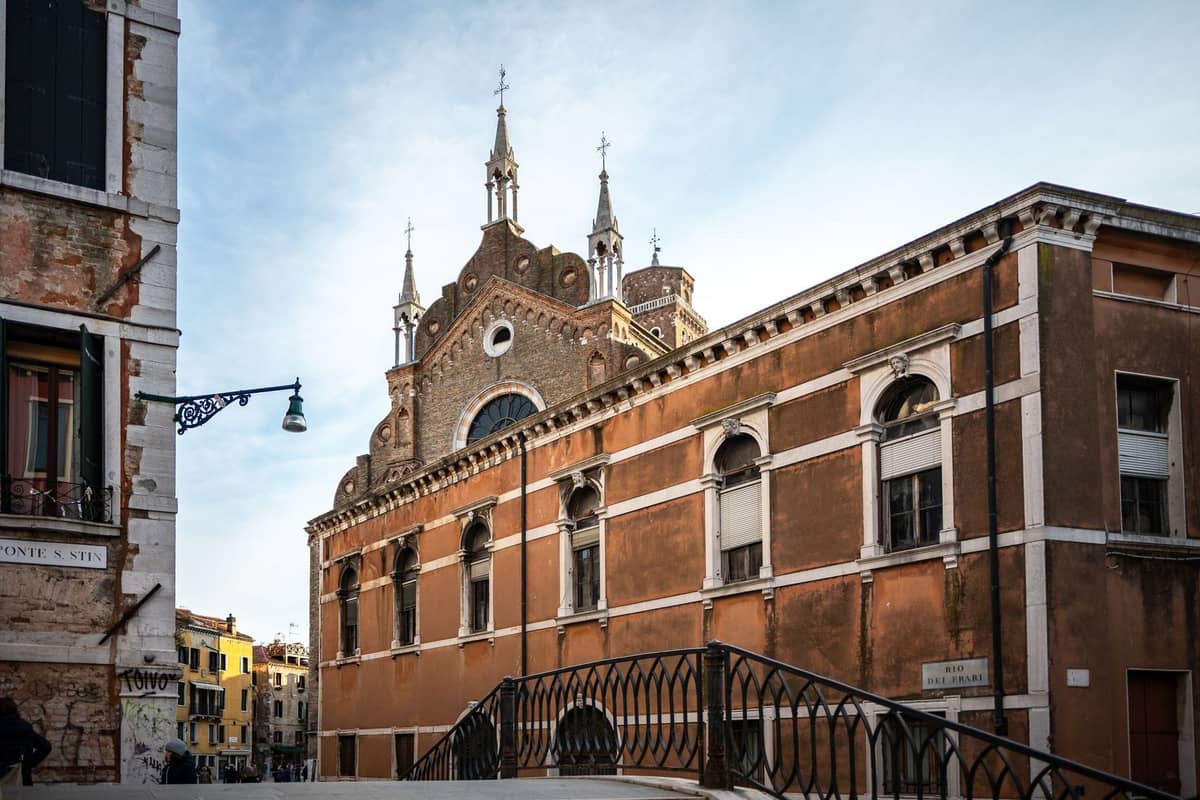 Die Chiesa della Madonna dell'Orto in Cannaregio, Venedig, mit ihrer gotischen Backsteinfassade, Spitzbögen, sichtbaren Türmen und einer nahen Kanalbrücke.