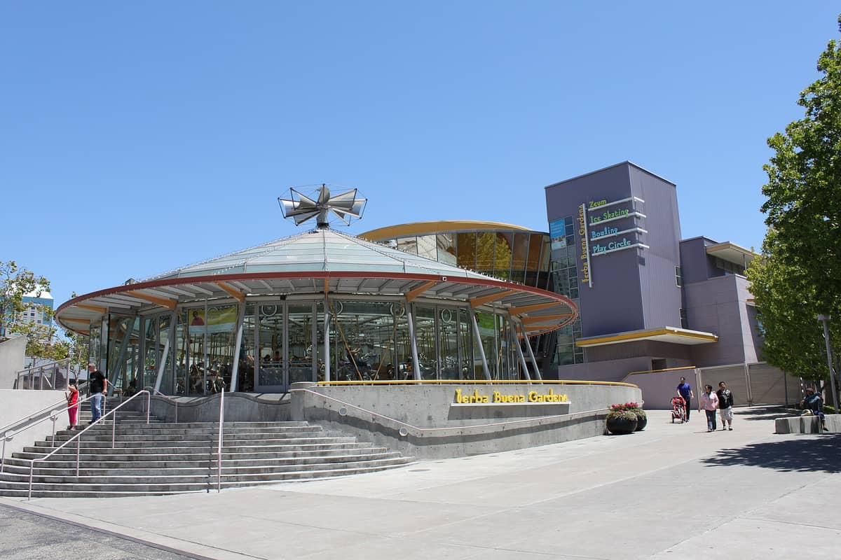 Esterno del Children's Creativity Museum a San Francisco con il moderno edificio in vetro della giostra e la chiara segnaletica dei Yerba Buena Gardens in una giornata di sole.