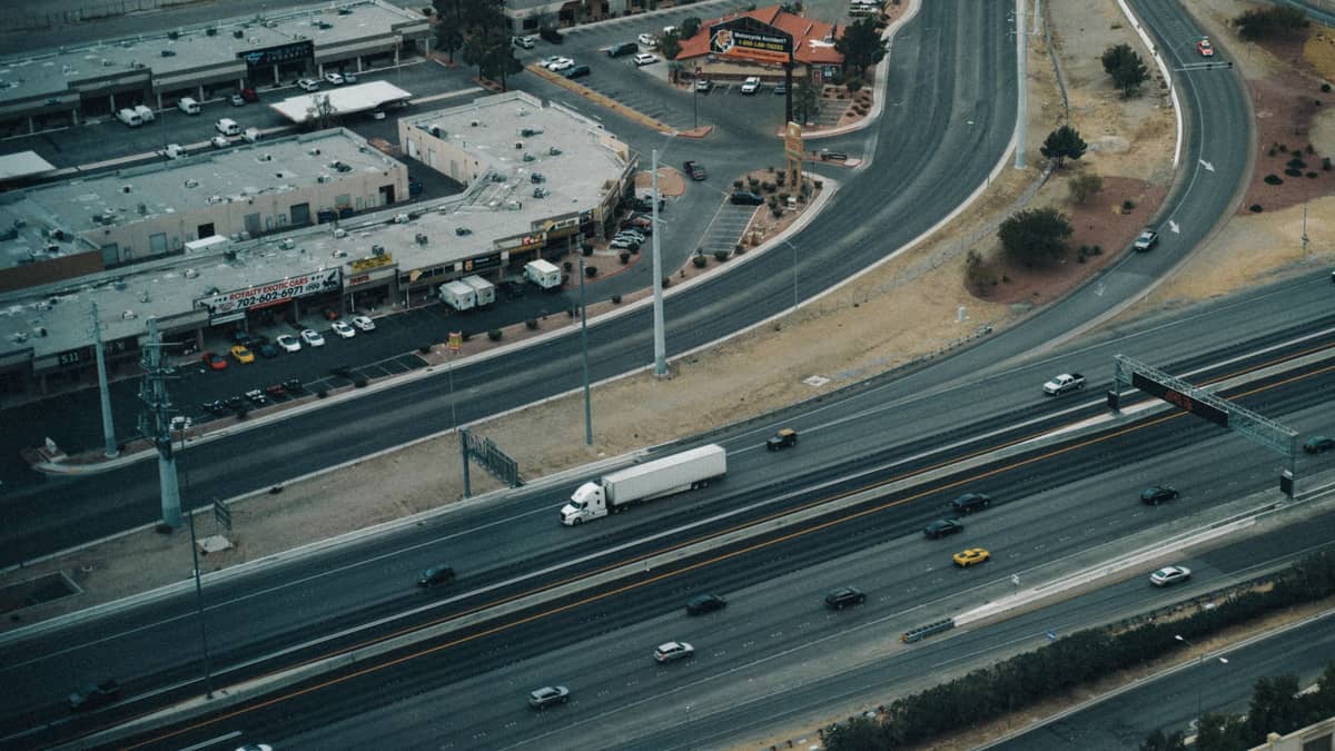 Aerial view of Spring Mountain Road in Las Vegas featuring strip malls and visible Asian businesses along a commercial corridor, with cars on the street.