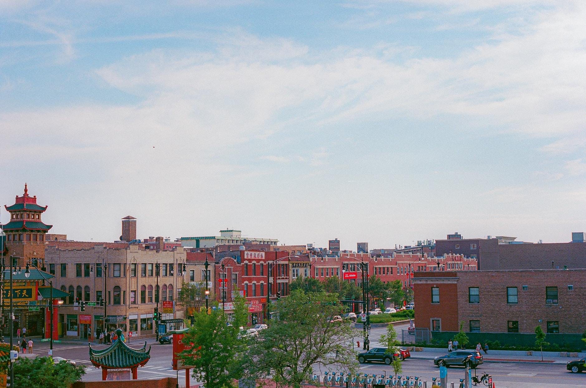 Vista diurna della Chinatown di Chicago, con architettura tradizionale cinese, edifici rossi, tetti a pagoda e Wentworth Avenue sotto un cielo azzurro.