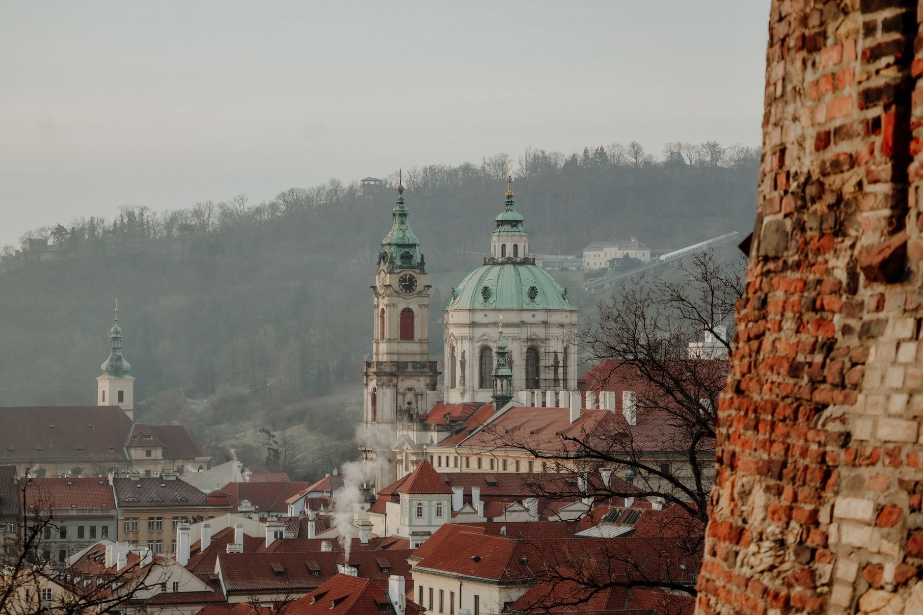 Vista della Chiesa di San Nicola con la sua cupola verde rame che si innalza sopra i tetti di tegole rosse nel quartiere di Malá Strana a Praga.