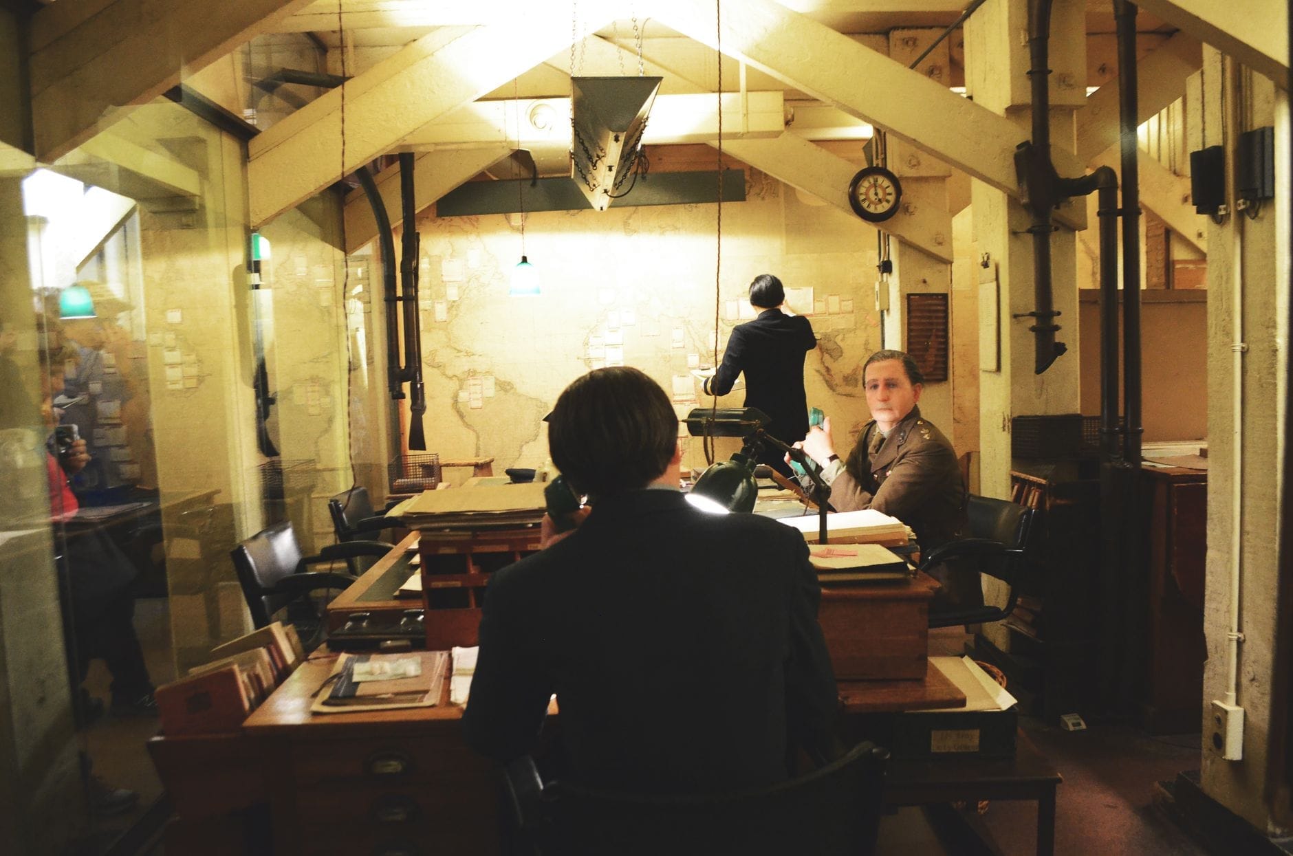 Sala di guerra sotterranea storica con mobili d'epoca, scrivanie, mappe e manichini in abiti anni '40 che ricostruiscono scene dal quartier generale segreto di Winston Churchill durante la Seconda Guerra Mondiale.