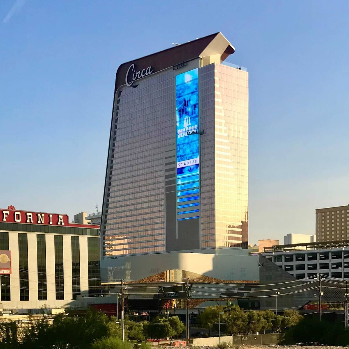 Menara tinggi Circa Resort & Casino yang menampilkan layar digital biru besar berdiri menonjol di pusat kota Las Vegas di bawah langit yang cerah.