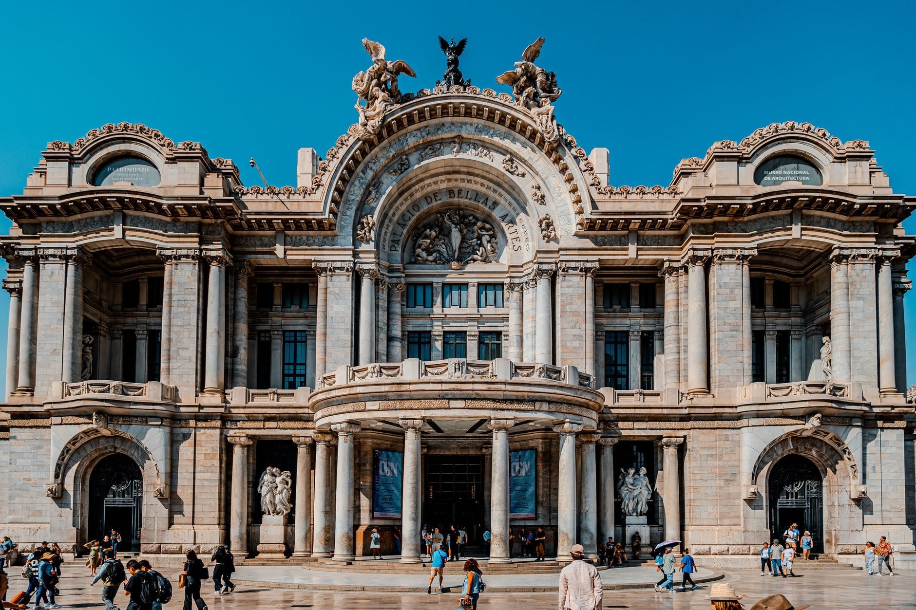 Vista ampia sulla facciata ornata del Círculo de Bellas Artes con persone che passeggiano davanti all'edificio, sotto un luminoso cielo blu madrileno.