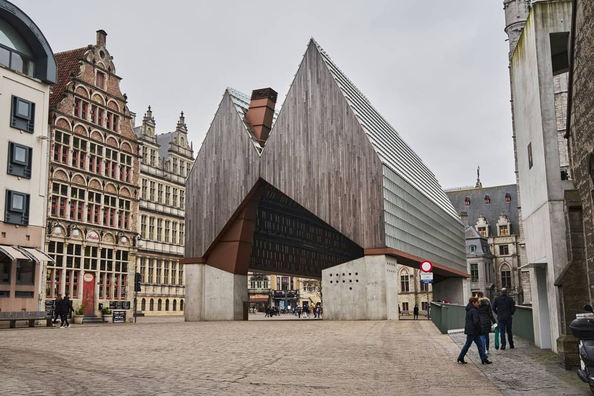 Wide view of Ghent's City Pavilion (Stadshal), showing its distinctive modern wooden canopy and angular structure surrounded by historic buildings in Emile Braunplein.