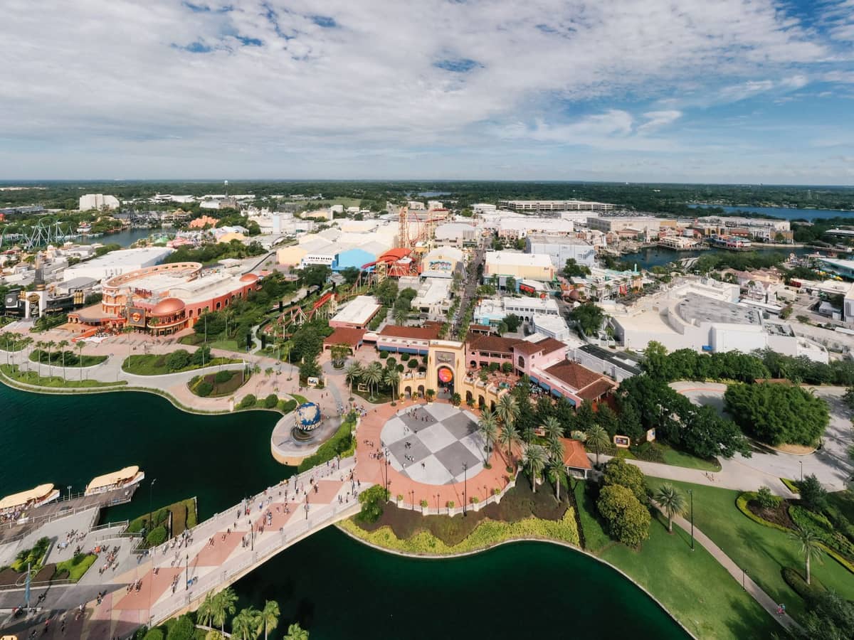Weitläufige Luftaufnahme des Universal CityWalk Orlando mit offenem Plaza, Wasserfront, bunten Gebäuden und Fußwegen, die zum Universal Orlando Resort führen.