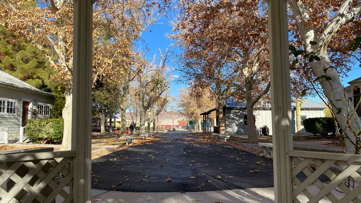 Vue depuis un kiosque sur Heritage Street au Clark County Museum, bordée de bâtiments historiques et d'arbres aux couleurs d'automne sous un ciel bleu dégagé.