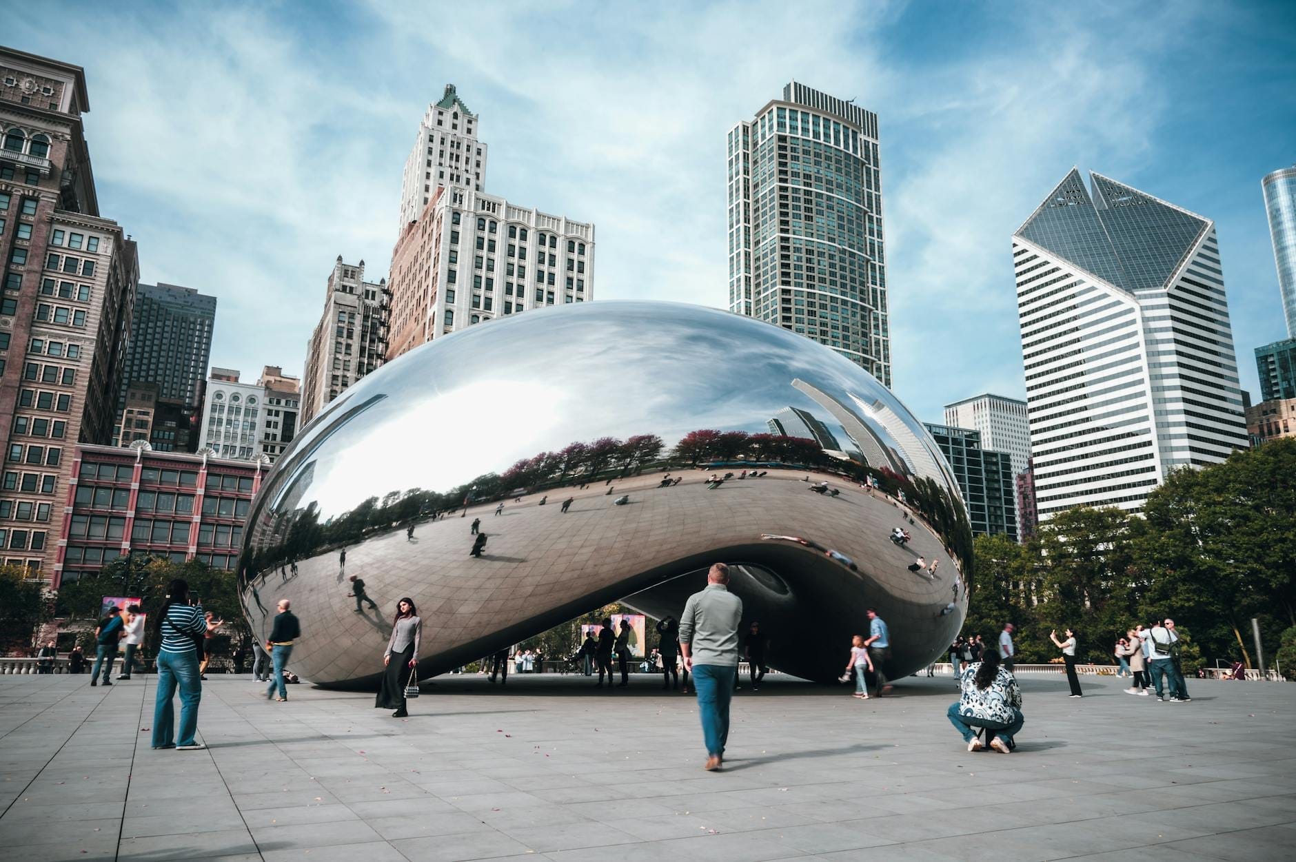 Cloud Gate, conosciuta come The Bean, riflette lo skyline di Chicago e i turisti in visita sotto un cielo azzurro nel Millennium Park.