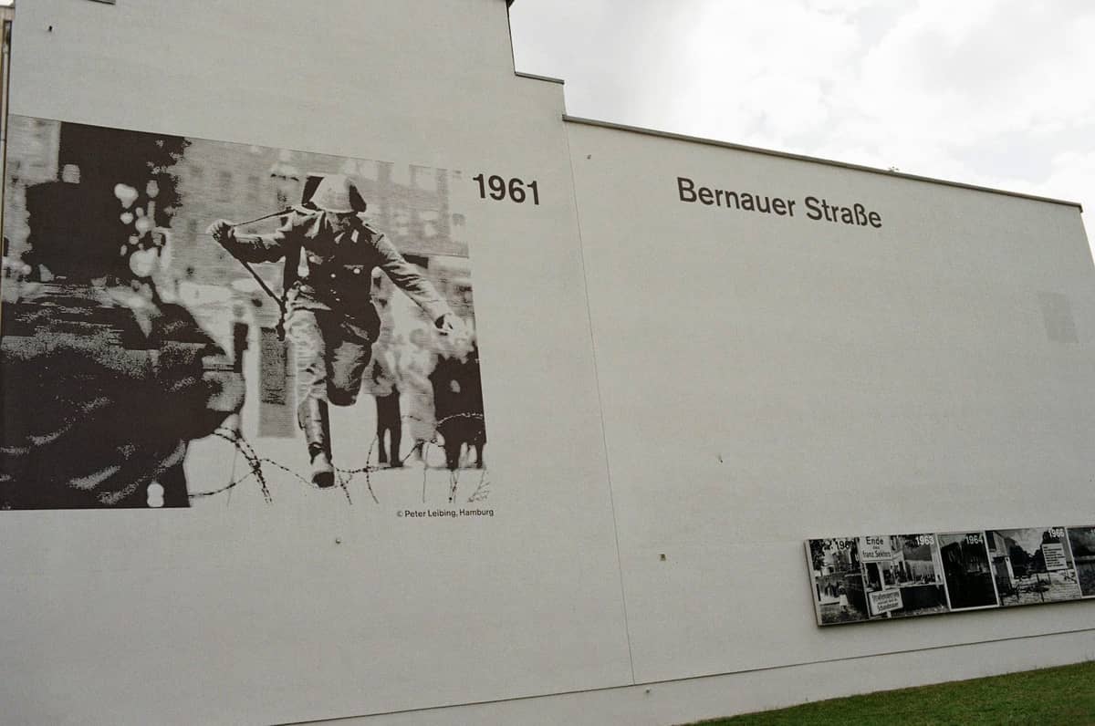 Eine Gedenkwand an der Bernauer Straße mit großen historischen Fotos aus dem Jahr 1961 und Informationstafeln, die die Gedenkstätte Berliner Mauer repräsentiert.
