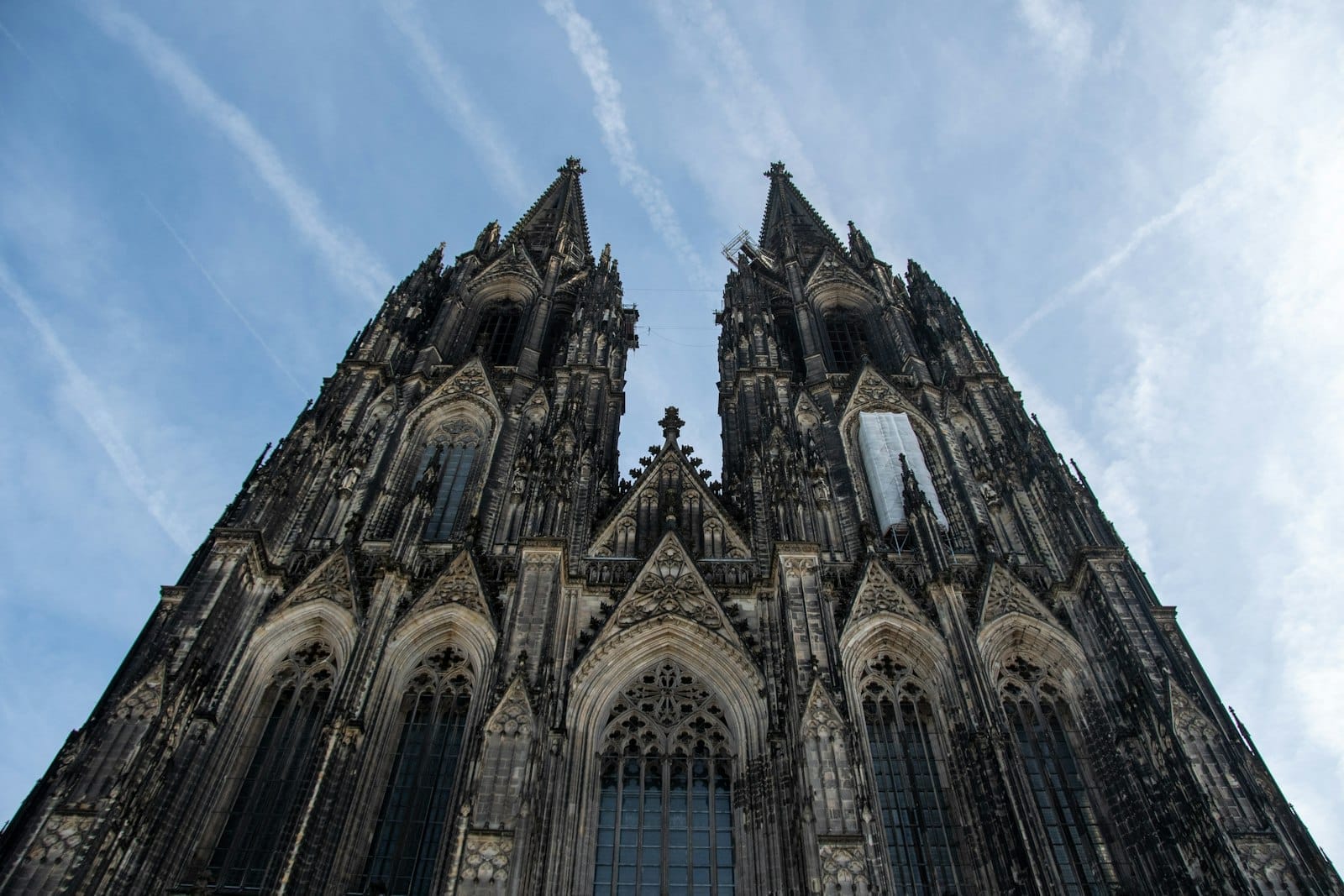 ยอดแหลมคู่สไตล์โกธิคของ Cologne Cathedral โดดเด่นตระหง่านตัดกับท้องฟ้าสีฟ้าสดใส พร้อมรายละเอียดงานแกะสลักหินและสถาปัตยกรรมอันงดงาม
