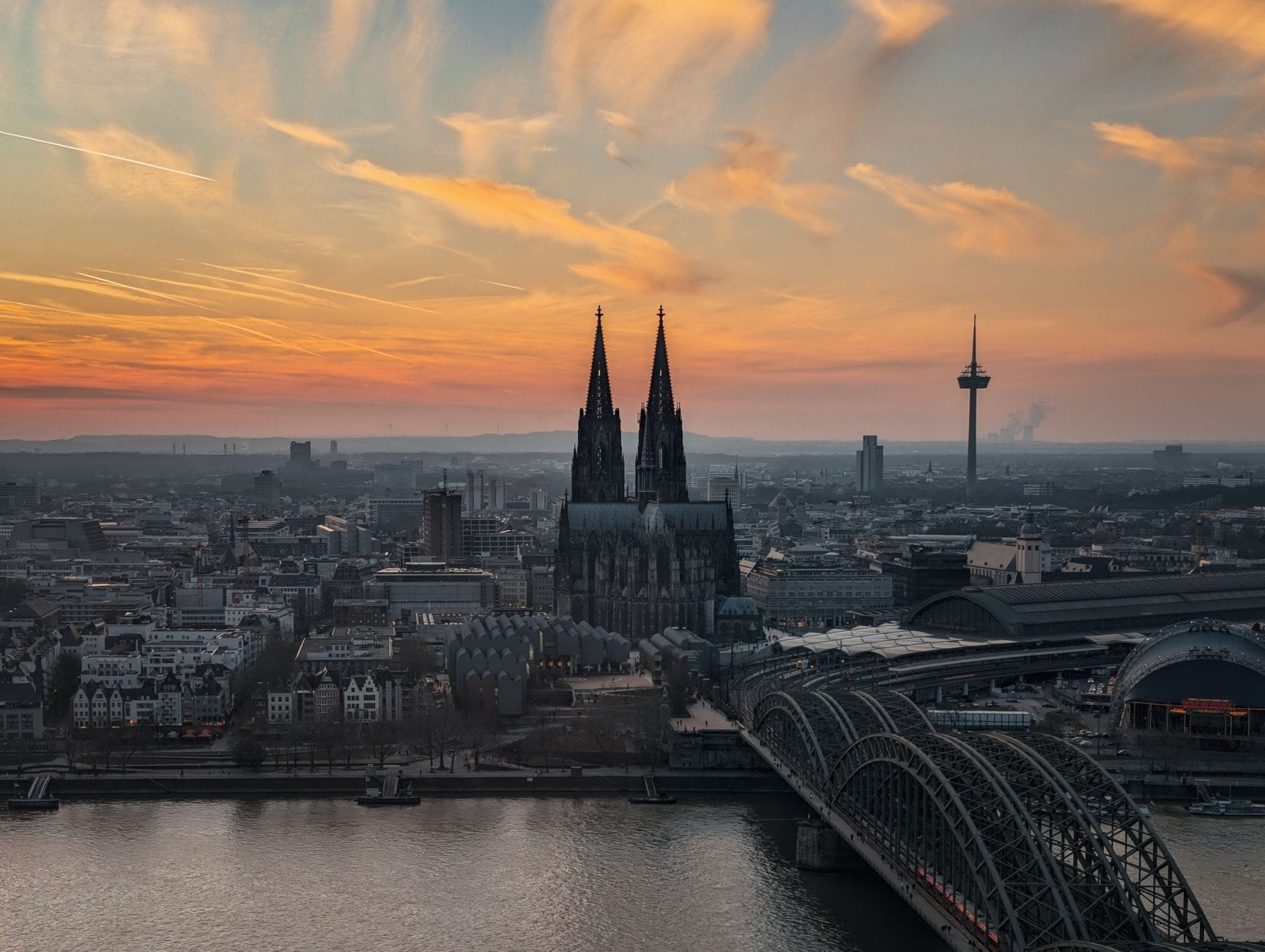 มุมมองทางอากาศของเมือง Cologne ยามพระอาทิตย์ตก แสดงให้เห็นมหาวิหาร สะพาน Hohenzollern และเส้นขอบฟ้าของเมืองริมแม่น้ำ Rhine