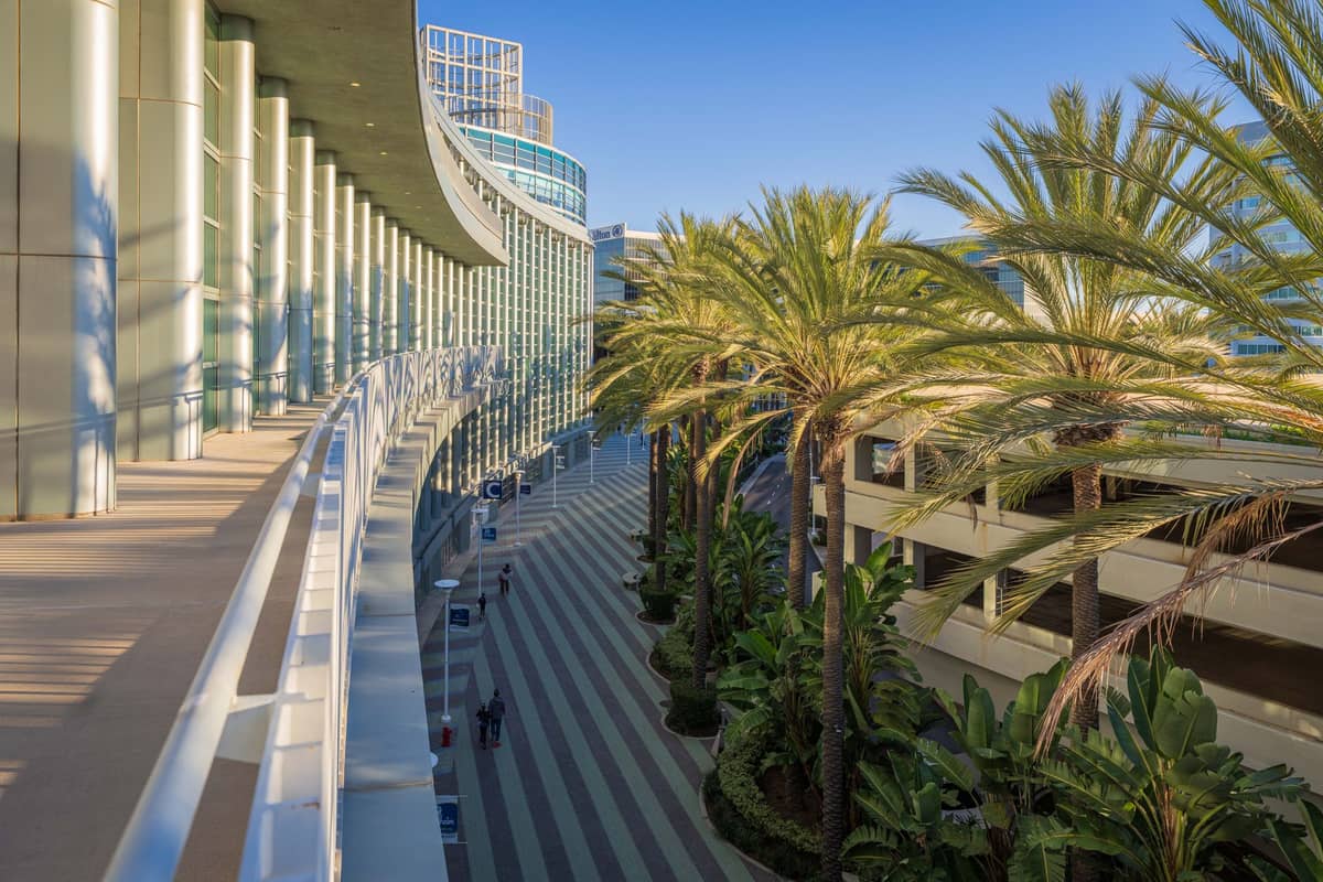 Außenansicht des modernen San Diego Convention Center mit Palmen und geschwungener Glasfassade unter klarem Himmel.
