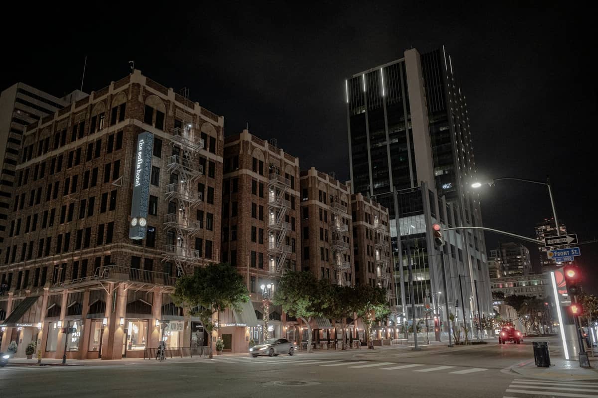 Nachtansicht der Hotels und modernen Hochhäuser in der Innenstadt von San Diego, mit Straßenlaternen, die die Gegend beleuchten, und wenigen Autos auf der Straße.