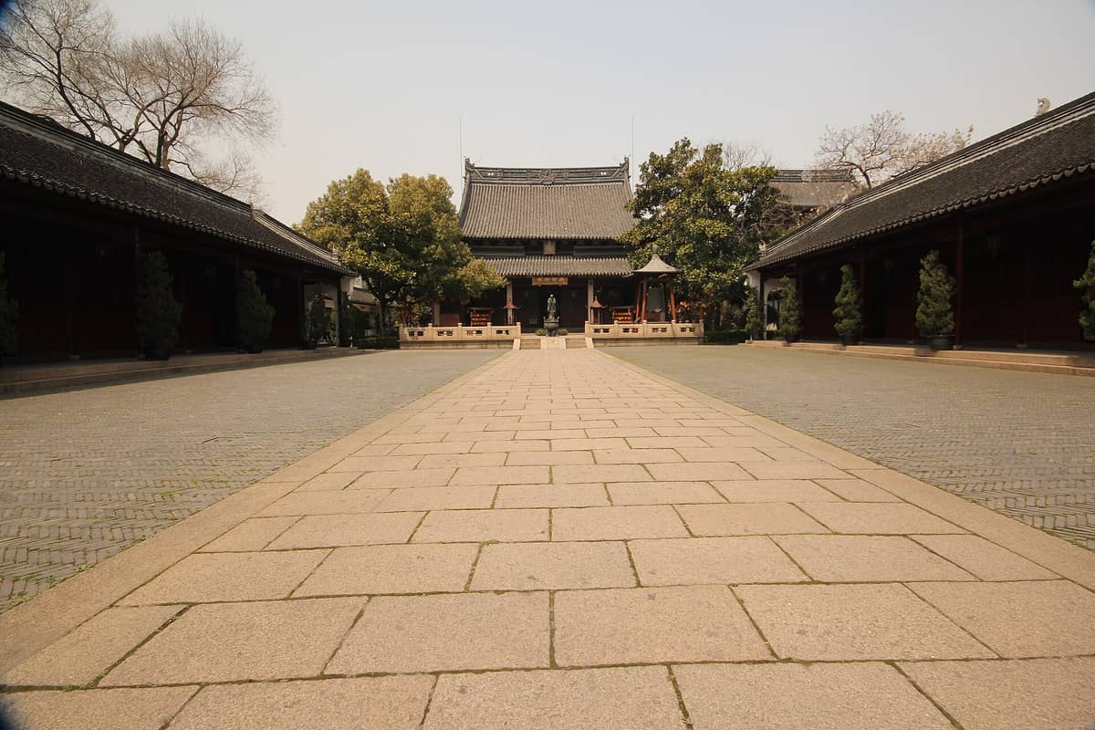 Ein weitläufiger Steinhof führt zur Haupthalle des Shanghaier Konfuzius-Tempels, flankiert von symmetrischen Wandelgängen und traditionellen chinesischen Dachlinien.