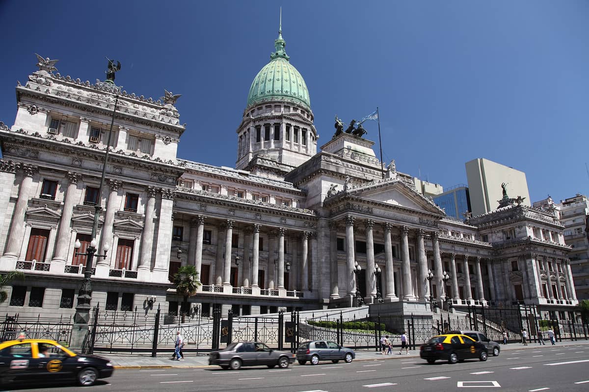 บรรยากาศช่วงกลางวันของ Palacio del Congreso de la Nación Argentina ในบัวโนสไอเรส โชว์ซุ้ม Neo-classic กับโดมสีเขียวอ่อน ติดถนนที่มีรถแท็กซี่วิ่งผ่านหน้าตึก