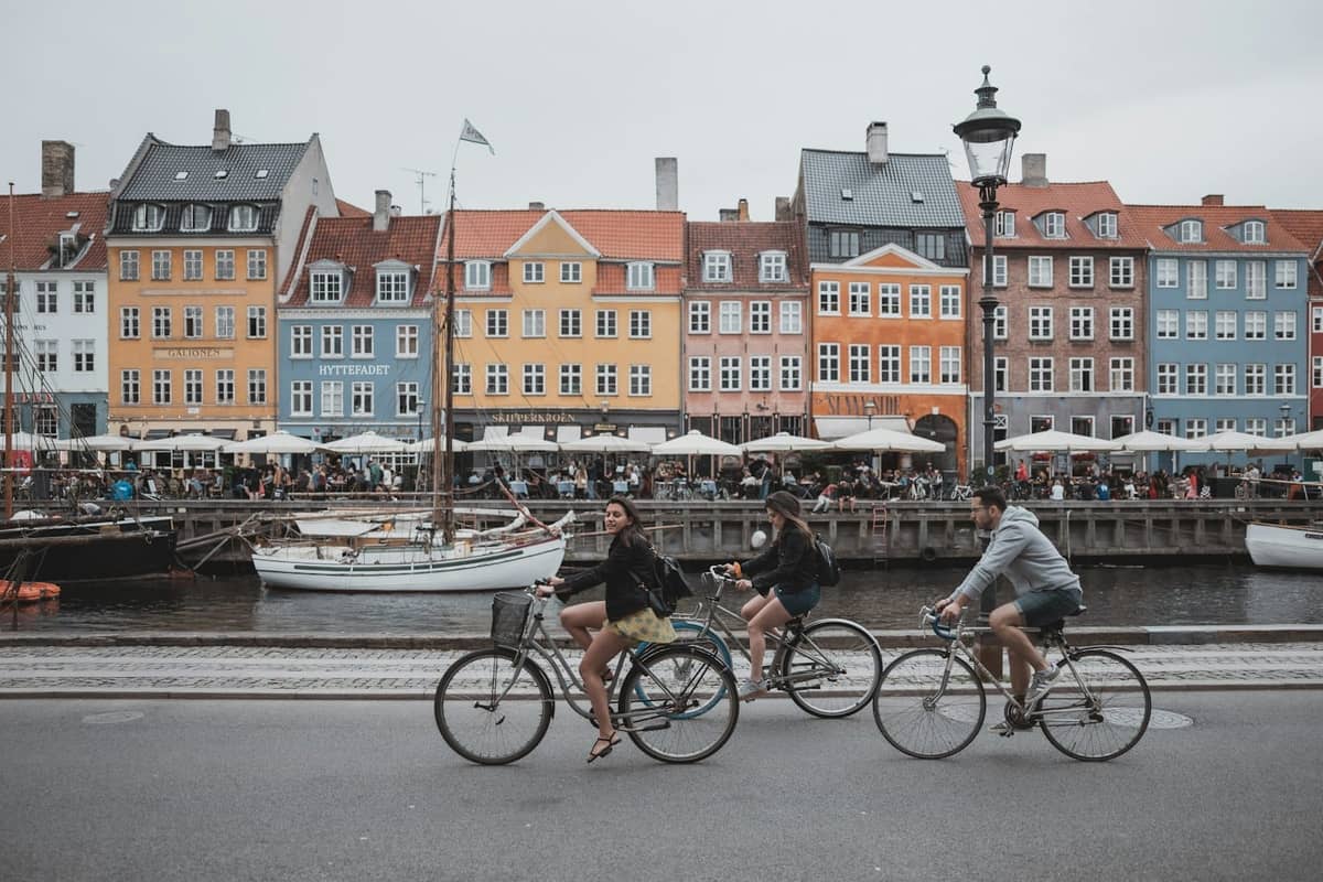 Des personnes à vélo devant les bâtiments colorés le long du front de mer de Nyhavn à Copenhague.