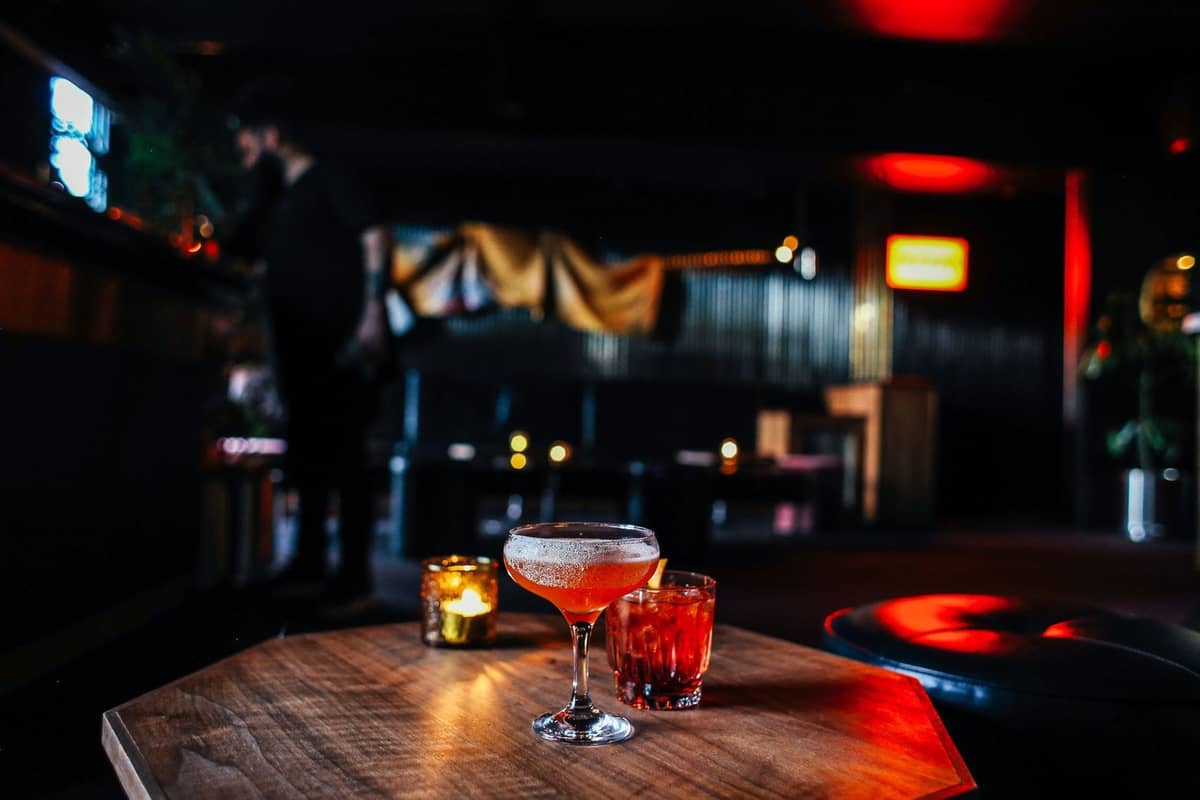 Kopenhag'da loş ışıklı bir bar içi, masada kokteyller, rahat oturma alanları ve sıcak ambiyans aydınlatması.