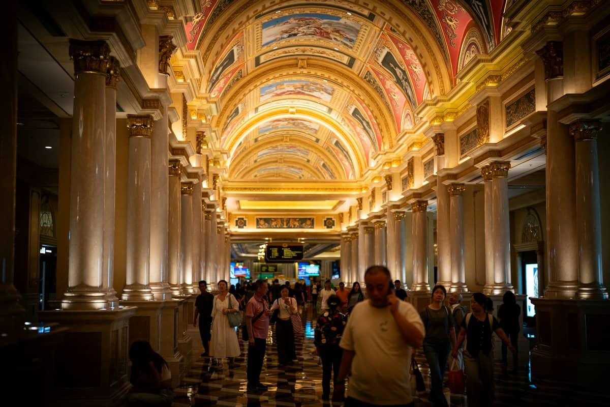 Menschenmassen, die unter verzierten, beleuchteten Bögen und Säulen in einem luxuriösen Einkaufsbereich im The Venetian Macau spazieren.