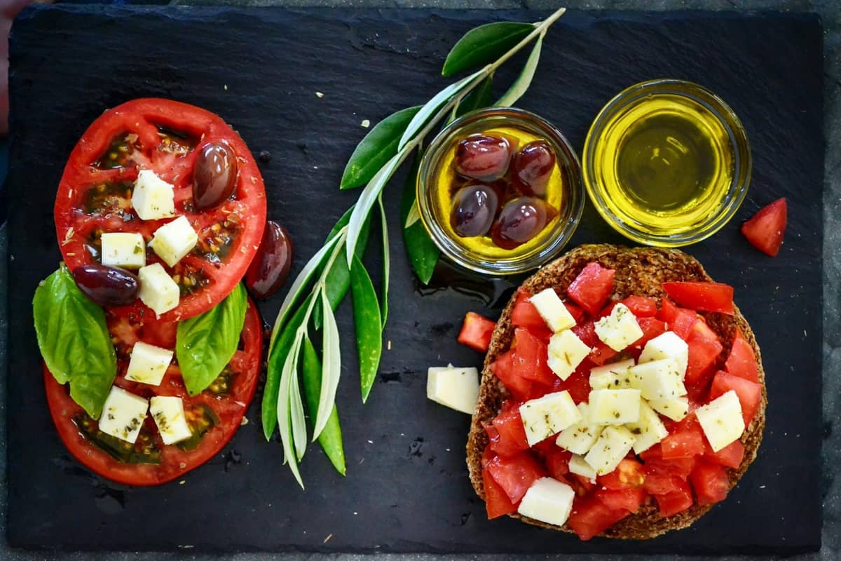 Plato de dakos con tomates en cubos, queso, aceitunas, aceite de oliva y hierbas frescas, un clásico plato cretense.