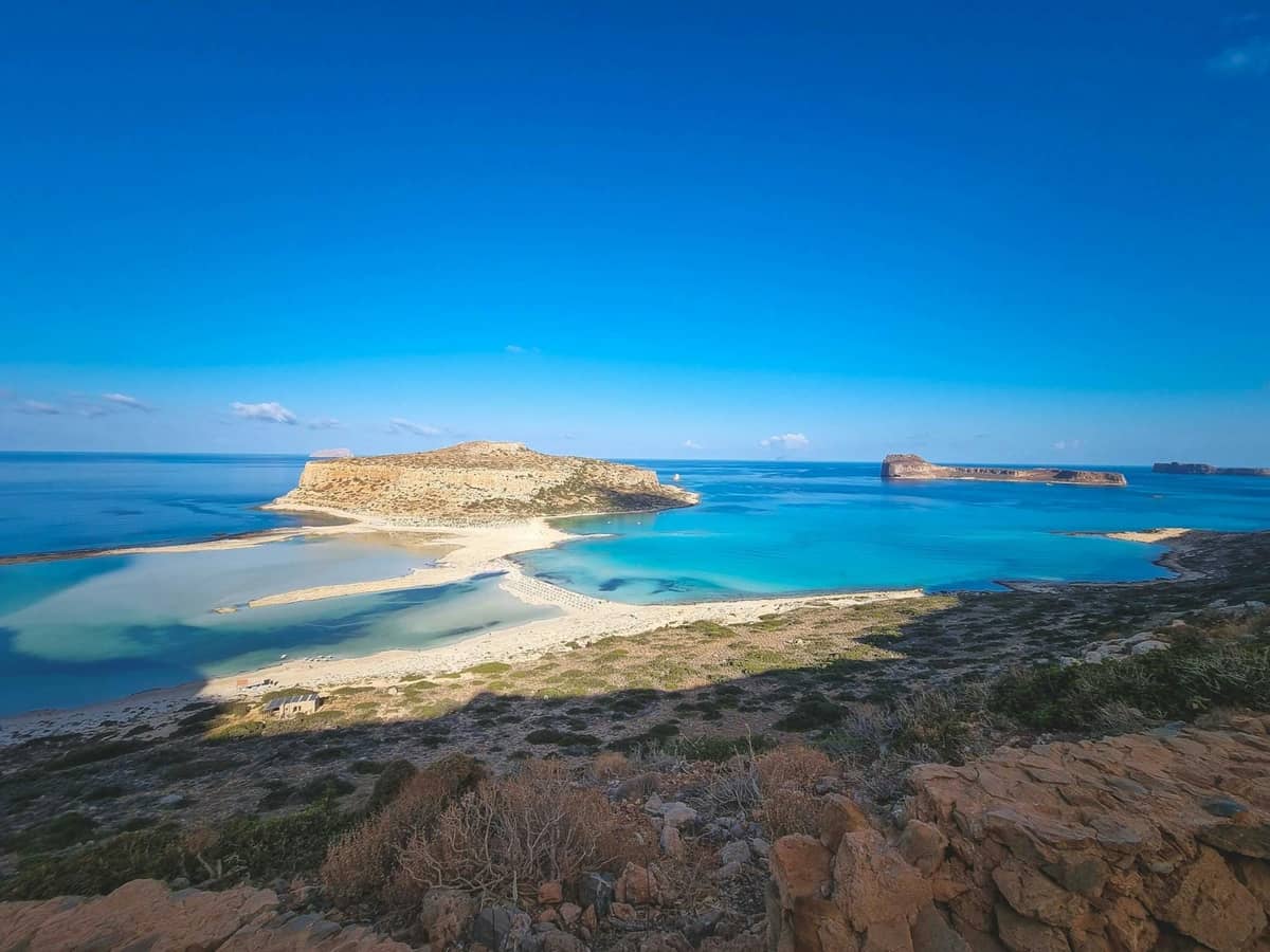 Vista panoramica della Laguna di Balos con acque turchesi, distese di sabbia e l'isola di Gramvousa sotto un cielo azzurro nel nord-ovest di Creta.