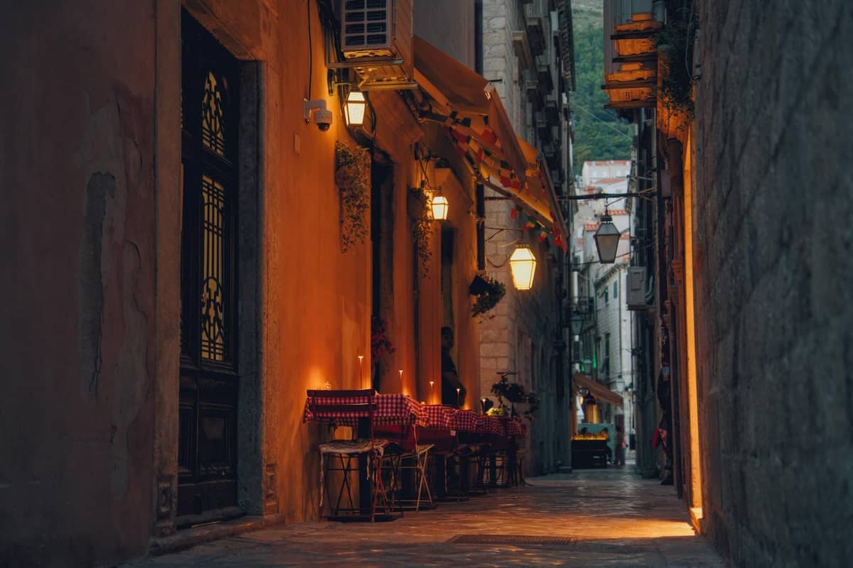 Romantisches Abendessen im Freien an Kerzenlicht-Tischen in einer engen kretischen Gasse mit warmem Lichtschein und traditioneller Dekoration.