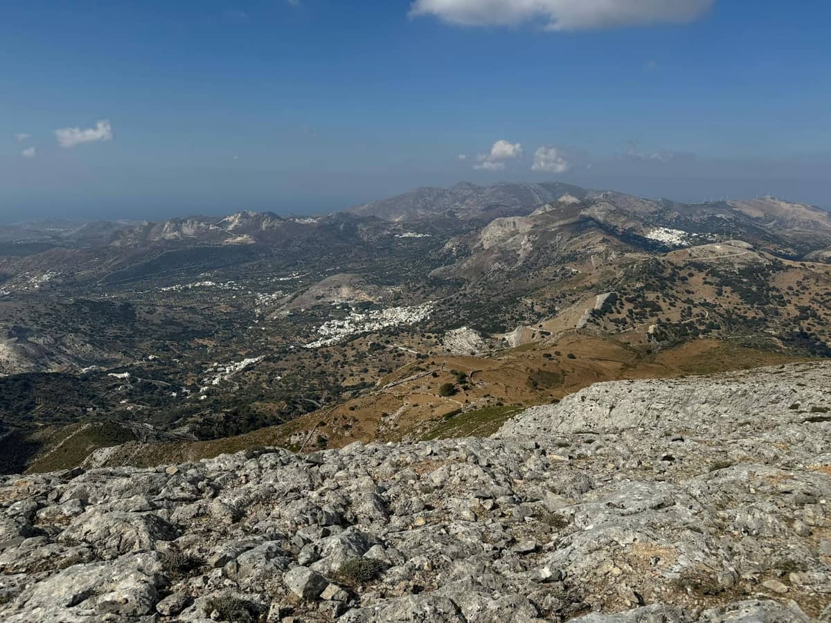 Paesaggio montano con villaggi sparsi e terreno accidentato sotto un cielo limpido, che evoca l'entroterra remoto dell'Altopiano di Lassithi a Creta.