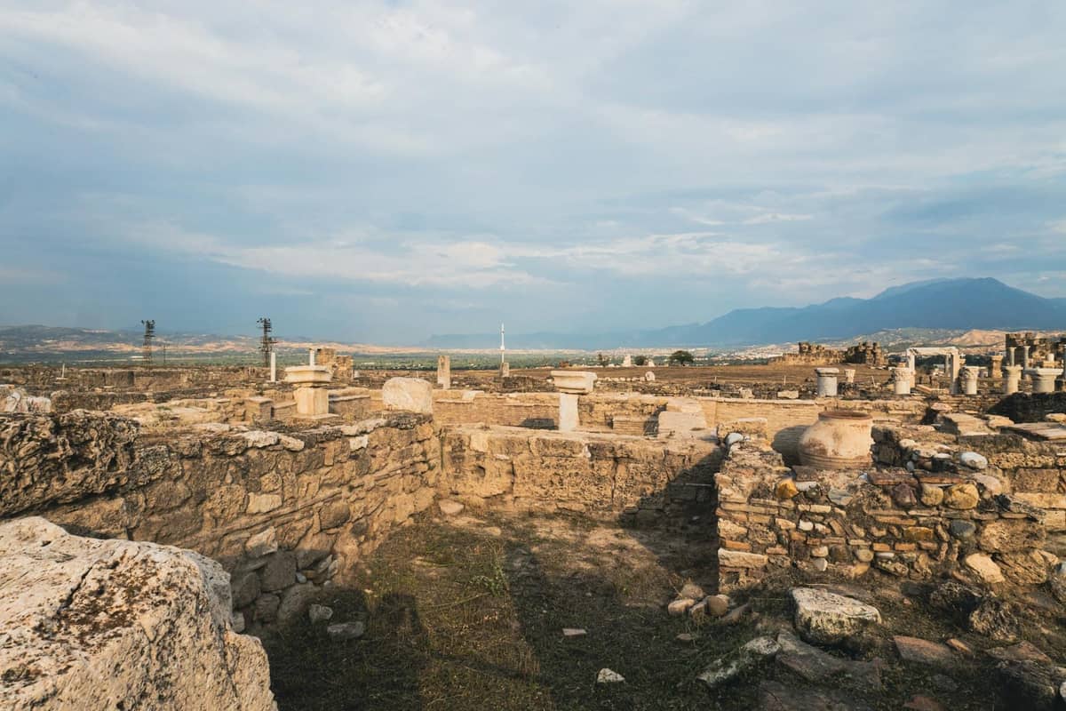 Vista ampia di antiche rovine in pietra e colonne nella pianura di Messara con paesaggio altipiano e montagne lontane a Creta.