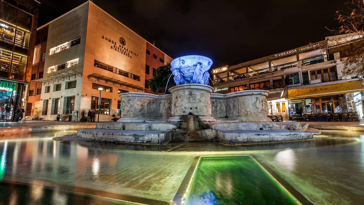 Nocny widok na znany plac w Heraklionie z oświetloną wenecką fontanną, restauracjami i barami otaczającymi tętniący życiem obszar.