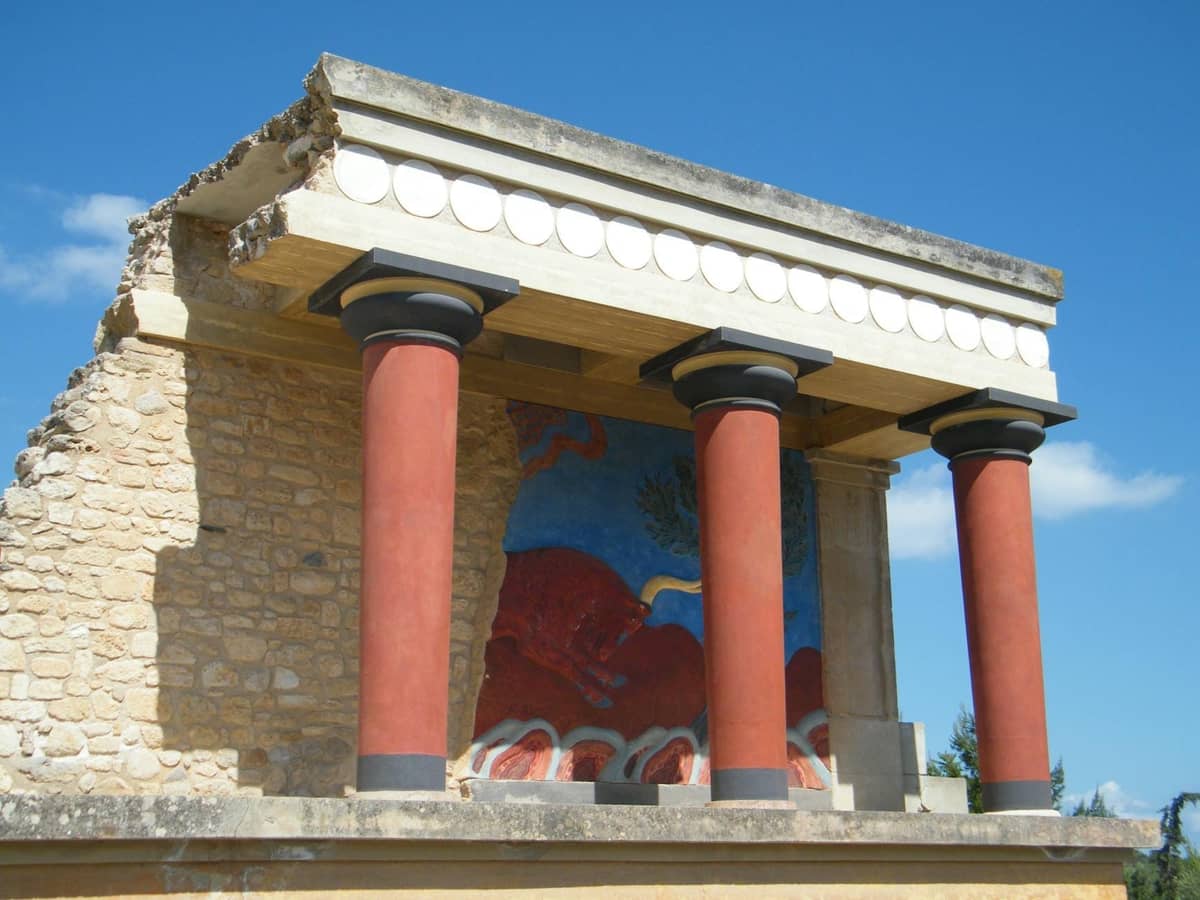Vista parziale delle colorate rovine e degli affreschi del Palazzo di Knossos sotto un cielo azzurro, un iconico sito archeologico vicino alle cantine di Creta.